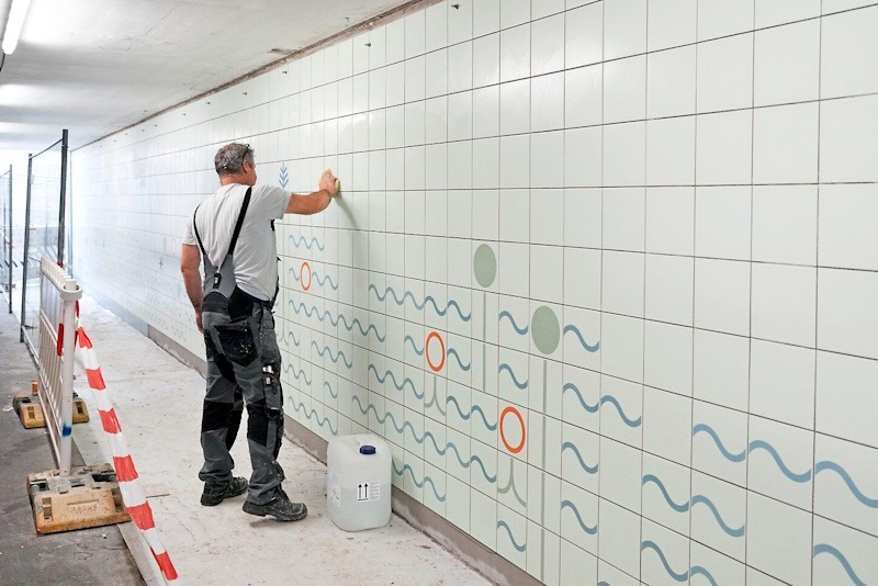 Mann legt Fliesen im Personentunnel